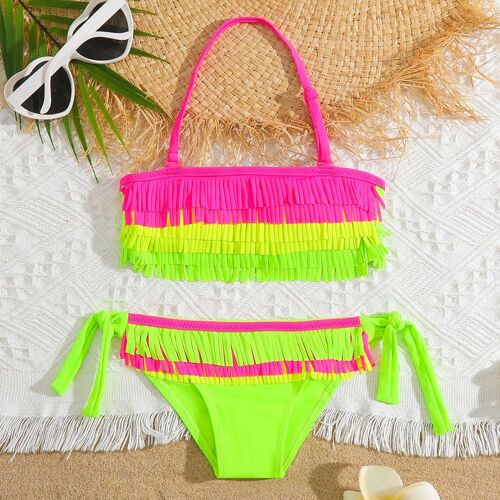 Neonfarbener Bikini mit Fransen und Sonnenbrille auf einem weißen Strandtuch.