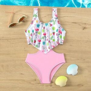 Rosa und weißer Badeanzug mit Flamingo-Muster, Sonnenbrille und Muscheln auf Holztisch.