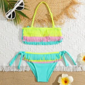 Fransenbikini auf Strandtuch mit Sonnenbrille und Blumen.