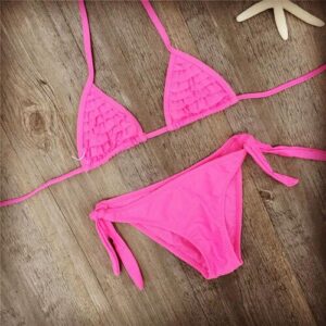 Pinker Bikini auf Holzboden mit Seestern-Dekoration.