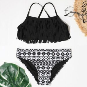 Schwarzer Fransen-Bikini mit gemusterten Unterteil, Sonnenhut und Brille auf weißem Hintergrund.